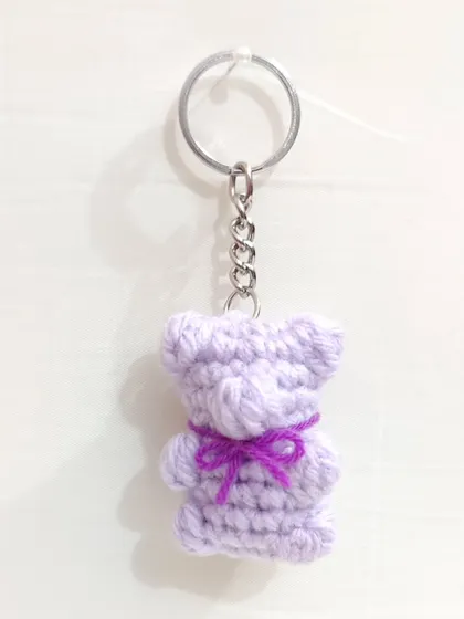 A lavender gummy bear keychain with a purple bow.