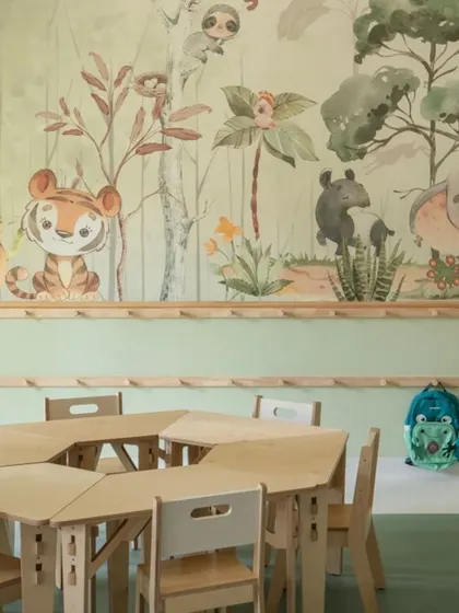 A detailed look at the forest wallpaper, featuring adorable illustrations of elephants, tigers, and sloths. The wooden peg rail below provides a practical and aesthetically pleasing spot for children to hang their bags.
