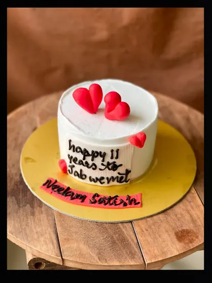 A sweet anniversary cake celebrating "11 years to jab we met." This cake features the couple's names, Neelam and Satish, and is adorned with cute 3D red hearts.