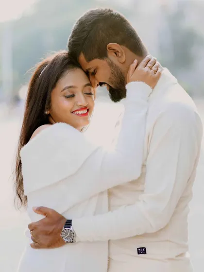 A tender moment between a couple dressed in white, captured in the warm, soft light of a city afternoon.