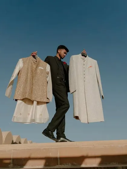 We believe that the couple's attire is an integral part of the wedding's design story. Here, a member of our team carefully prepares the custom-designed groomswear against the stunning backdrop of Jaisalmer.