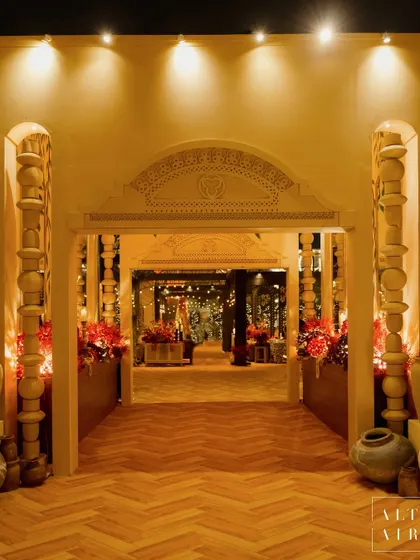 The grand entrance to the 'Mid-Century Mod' sangeet. The design featured earthy textures, sculptural pillars, and a herringbone wood floor, creating a seamless indoor-outdoor connection and a warm welcome.