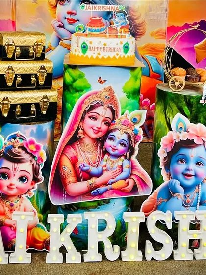 A detailed shot of the Krishna theme setup, highlighting the custom cutouts, light-up marquee letters for the name 'JAI KRISHNA', and themed props like miniature trunks and a decorative swing.