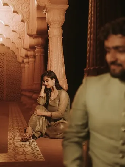 A moody and romantic pre-wedding shot in a historic-looking corridor, with the groom out of focus in the foreground.