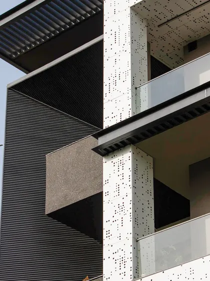 A close-up showing the contrast between the dark, fluted panels and the white, perforated jali. This juxtaposition of textures and colors is a key element of the modern design.