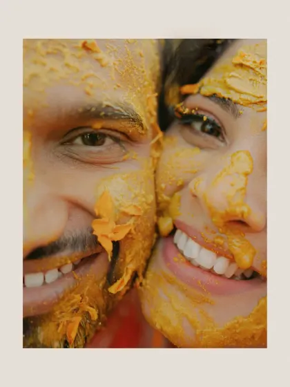An extreme close-up of the couple's smiling faces, covered in Haldi. This shot is all about raw emotion and happiness.
