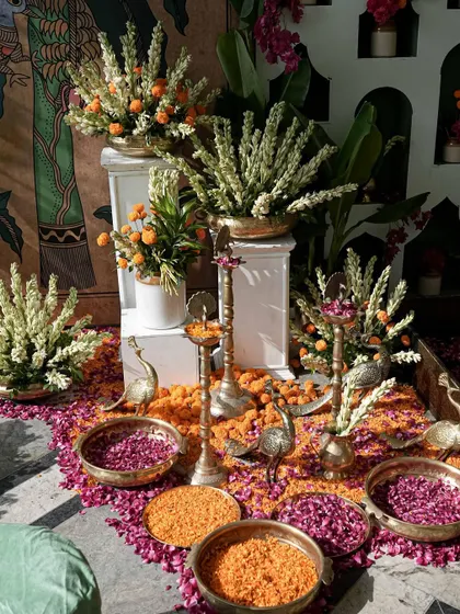 A complete view of the haldi floral setup, with brass peacocks, diyas, and bowls of fresh petals ready for the ceremony.