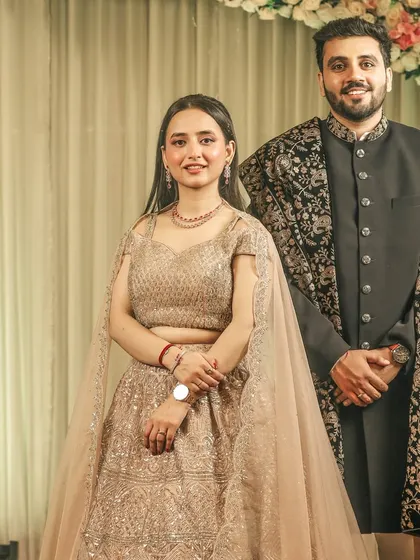 A classic, formal portrait of the newly engaged couple, standing against a simple backdrop.