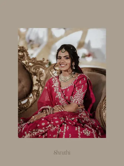 An elegant solo portrait of the bride seated on a throne-like chair, looking radiant in her pink lehenga.