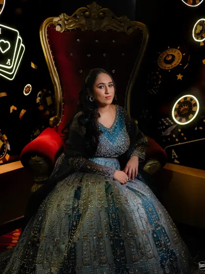 A regal bridal portrait at a casino-themed Sangeet on a cruise. The unique decor and the bride's confident pose make for a truly memorable shot.