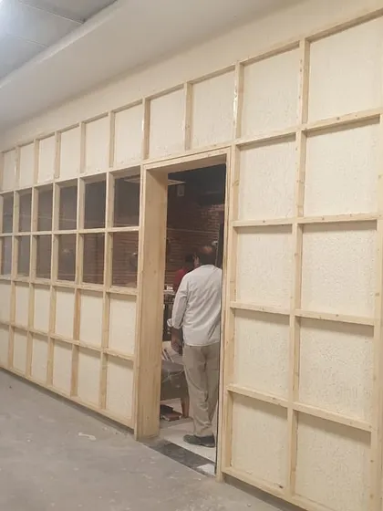 The "before" shot of an entrance wall at Yoko Sizzlers, showing the custom wooden grid frame we built to house the art installations.