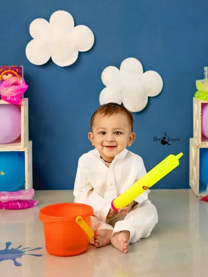 A bright, smiling portrait of a baby boy enjoying the festive Holi atmosphere in the studio.