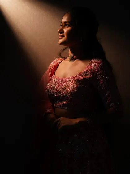 A dramatic shot highlighting the intricate embroidery on the blouse of the pink lehenga. Even in low light, the craftsmanship and detail shine through, making it a piece to be remembered.