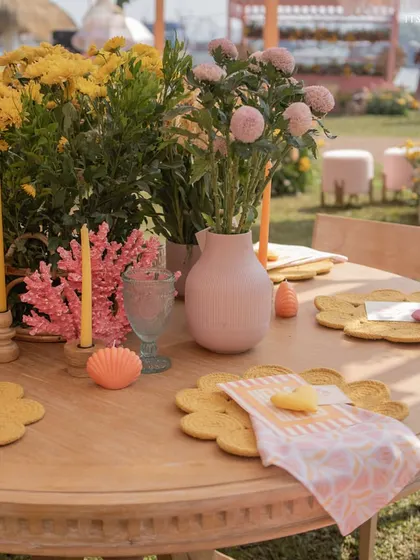 A close-up of the brunch tablescape, featuring flower-shaped placemats, colorful candles, and fresh yellow and pink flowers.