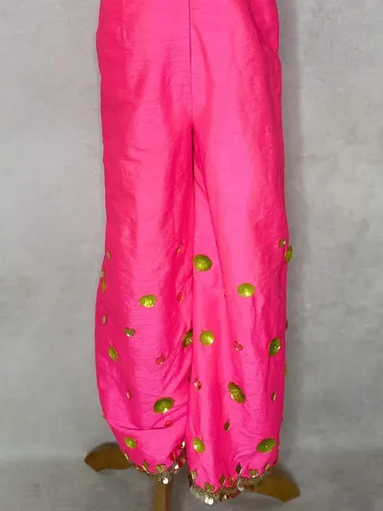 A detail shot of the fluorescent pink jumpsuit, showing the sequin work on the pants.