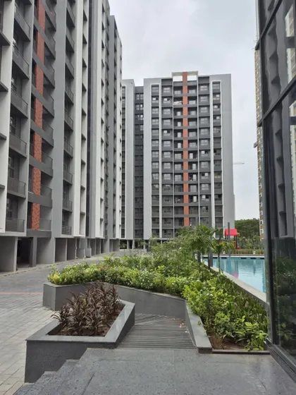 This view of Adani Amogha in Ahmedabad shows the relationship between the residential towers and the landscaped podium, which includes a swimming pool and green areas for the community.