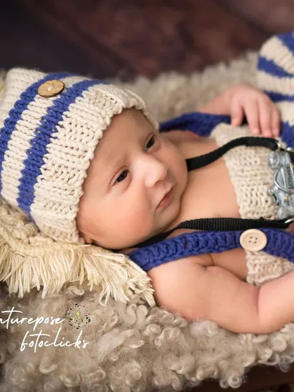 An awake newborn holding a miniature camera, a fun prop for a future photographer.