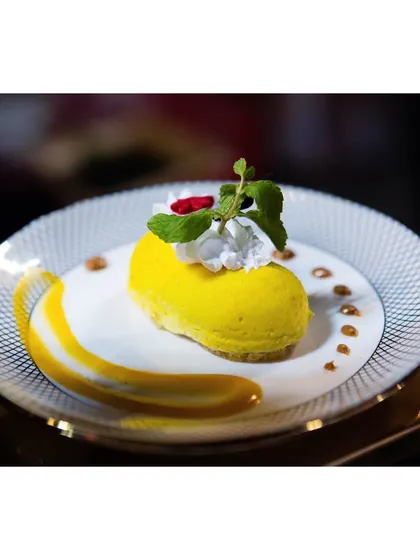 A luscious mango mousse cake, shaped elegantly and garnished with fresh mint. This dessert is a celebration of the king of fruits.