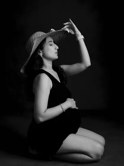 A stylish black and white portrait with a hat prop. The dramatic lighting creates a chic, fashion-inspired look.