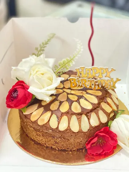 A whole wheat jaggery cake decorated with flowers, a healthier option for a birthday celebration.