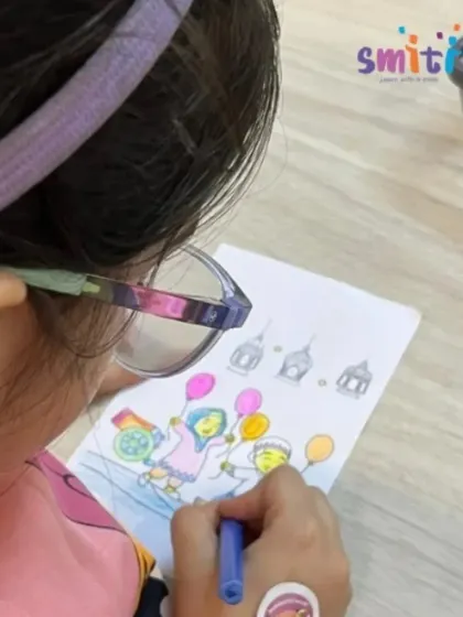 A girl wearing glasses concentrates on her coloring sheet, adding vibrant hues to a festive scene. We provide inclusive activities that allow every child to participate and shine.