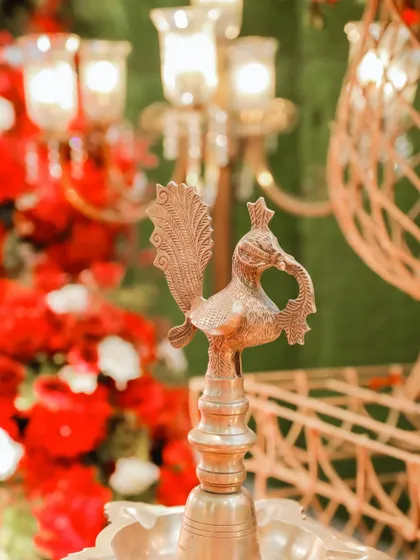 Traditional details matter. A close-up of a brass peacock lamp, an element that adds to the royal and authentic feel of a traditional Indian wedding.