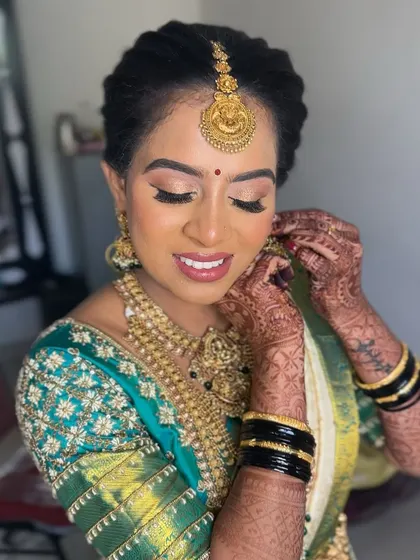 A close-up of the final touches. The soft gold eyeshadow and radiant skin create a look that is both classic and modern, perfect for a South Indian bride.