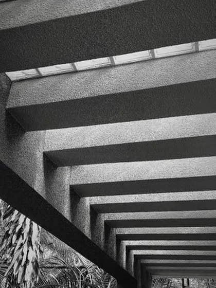 The play of light and shadow brings my designs to life. Here, the strong lines of concrete beams create a powerful rhythm, while a skylight filters soft light from above, demonstrating how texture and light can define an atmosphere.
