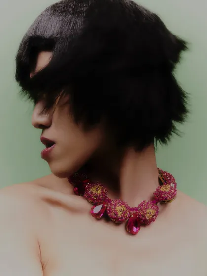 A profile shot showcasing another intricate, ruby-toned necklace. The styling is all about letting the statement jewelry piece be the star.