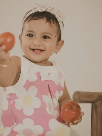 A sweet baby girl playing with tomatoes. We use simple, everyday objects to create fun and natural photo opportunities.
