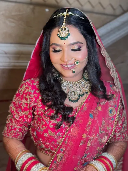 A happy, smiling bride in her pink lehenga. Her makeup is fresh and glowing, perfect for a day wedding.