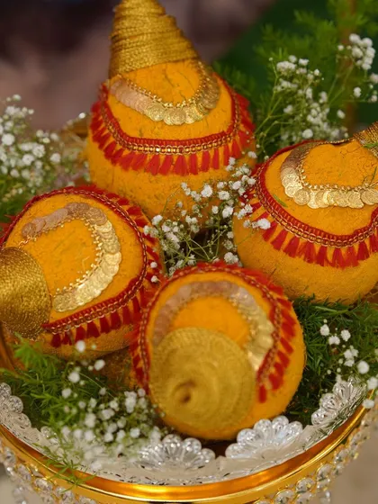 A close-up of my decorated coconuts, painted with turmeric and adorned with traditional gold-colored coins and threadwork.