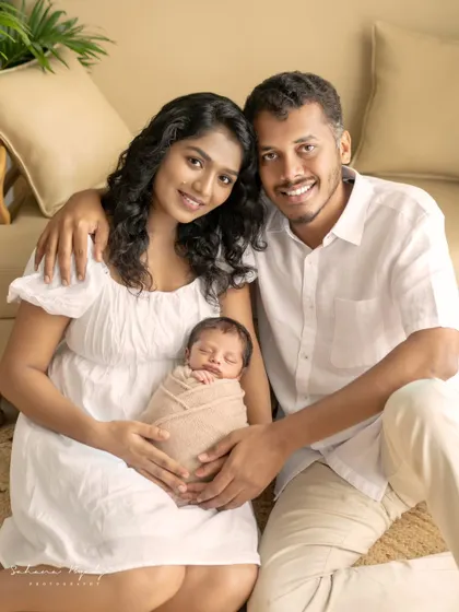 A smiling couple with their peacefully sleeping newborn. This photo captures the joy and contentment of starting a new family, a memory they will treasure forever.