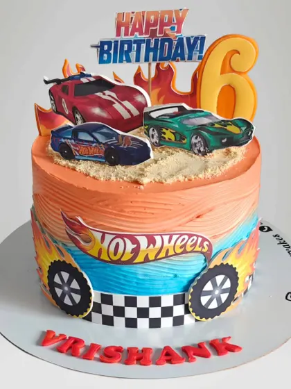 A fiery Hot Wheels cake for a 6th birthday. The orange and blue ombre frosting mimics the Hot Wheels logo, and the cake is topped with edible images of racing cars.