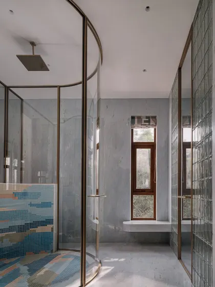 A full view of the master bathroom, showcasing the cylindrical shower, the colorful mosaic wall, and the large, open-plan layout.
