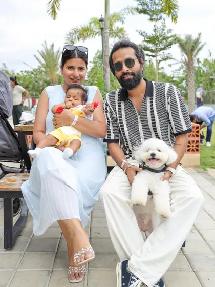 A modern family portrait: parents, a human baby, and a fur baby, all enjoying a day out at our community brunch.