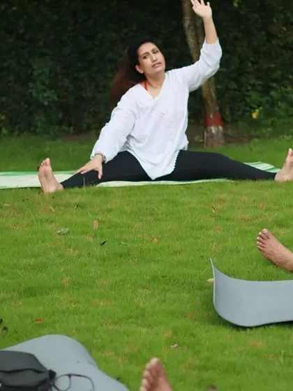 Guiding students in a seated forward bend during a park yoga session. This is a great way to calm the nervous system and stretch the entire back of the body.