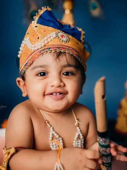 A joyful portrait of the baby as Krishna, holding a flute. His bright smile shows how comfortable and happy he is during the studio session.