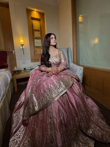 A full-length shot of the Roka outfit. The soft glam makeup perfectly complements the elegant pink and gold lehenga.