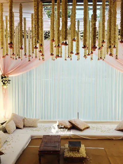 I designed a comfortable and stylish low-seating area for guests, set under the canopy of hanging floral garlands. The space was draped in soft fabrics and scattered with flower petals for a romantic feel.