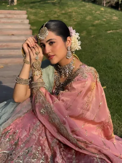 This seated portrait showcases the intricate hand jewelry and the beautiful floral bun, adding to the traditional charm of the look.