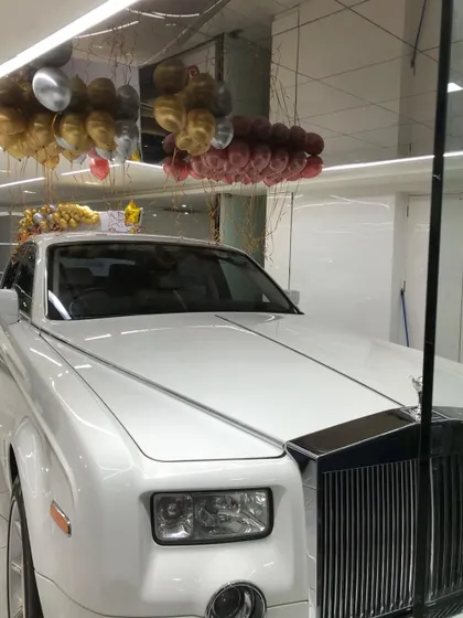 A shot from the Lucky Motors event, where elegant ceiling balloons float above a classic white Rolls Royce, enhancing the showroom's luxurious feel.