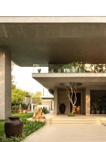 Views of the home from the garden, showing how the monumental concrete forms are softened by the surrounding greenery. The design creates a constant interplay between the architecture and the landscape.