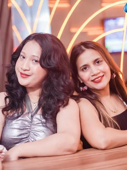 Two friends smiling together, enjoying the vibrant atmosphere of the party.
