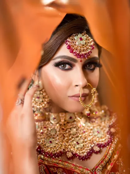 An artistic shot of a bride peeking through her dupatta. The focus is on her intense, beautifully defined eyes, a signature element of my bridal makeup services.