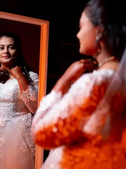 A beautiful portrait of a Christian bride in her white gown, adjusting her necklace in the mirror before the ceremony.