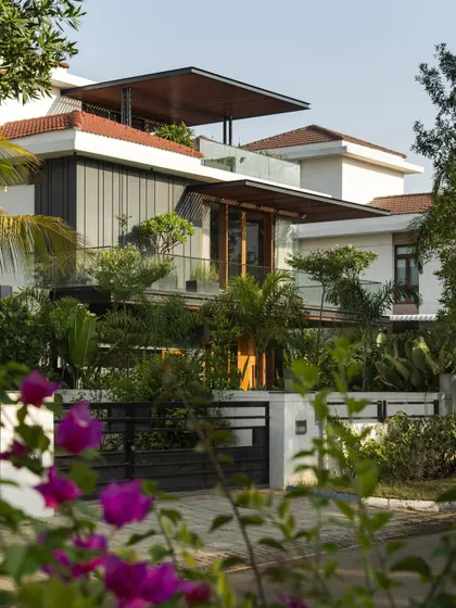 A view of Villa re:FORM through the surrounding landscape, showing how the architectural lines of the pergolas and facade integrate with the natural greenery.