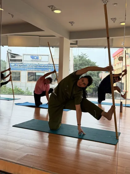 A group of students in a stick-supported side bend. The stick helps to lengthen the spine and deepen the stretch through the side of the body.