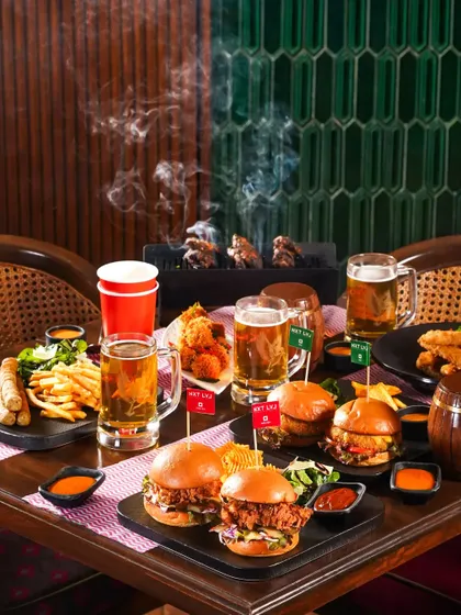 A full table spread for an Oktoberfest celebration, complete with burgers, wings, fries, and mugs of beer. This shot conveys a sense of a hearty, communal feast.