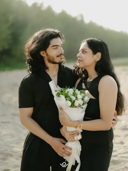 A romantic moment from a pre-wedding shoot, with the couple sharing a look as the bride holds a bouquet of white roses.